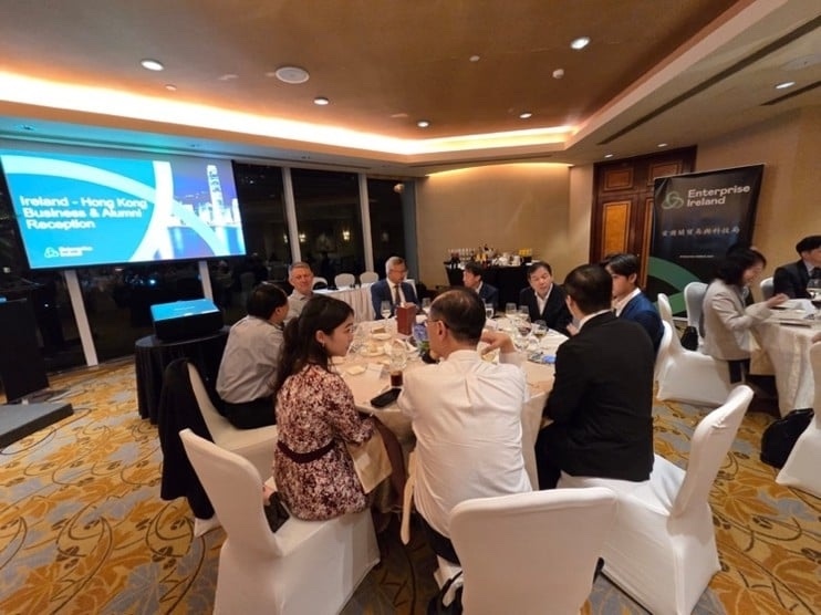 A dinner of round tables in a hotel ballroom, a presentation on screen