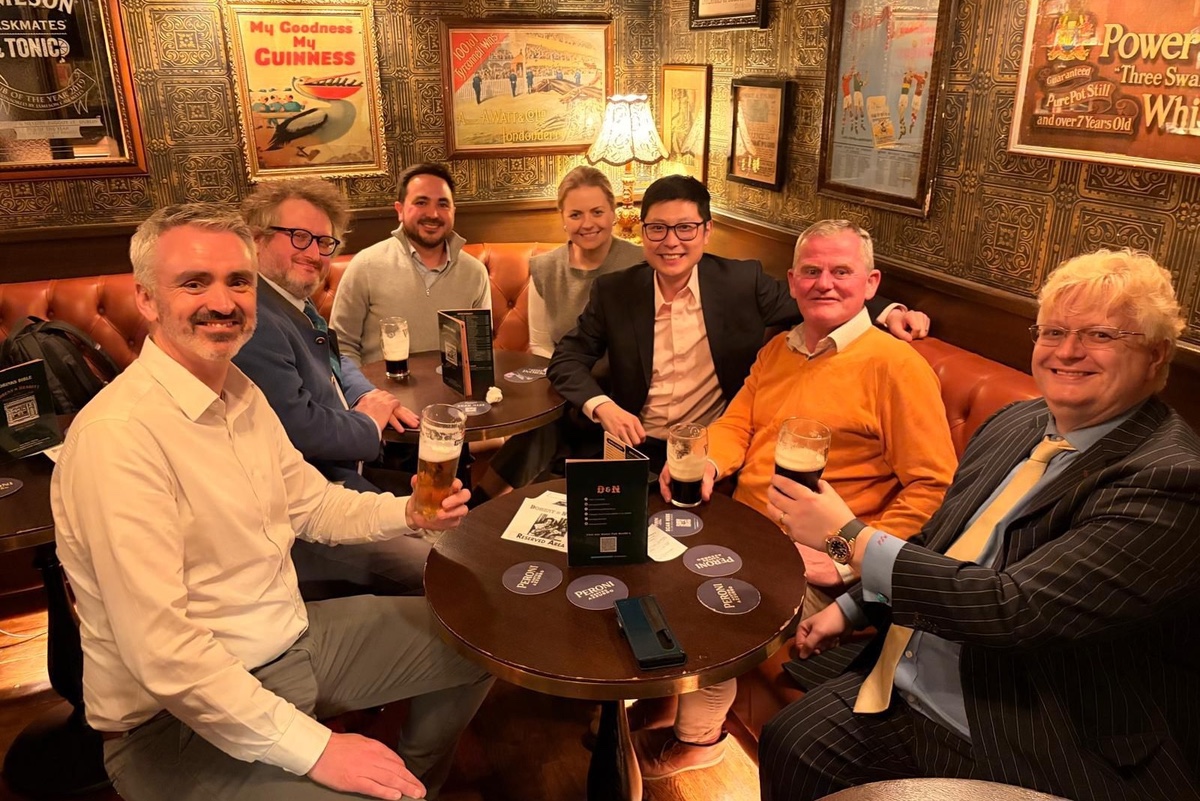 A group around a pub table with pints, old advertising signs on the walls