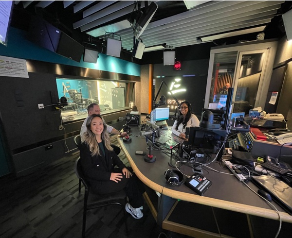 Two guests and a presenter at microphones in a radio studio